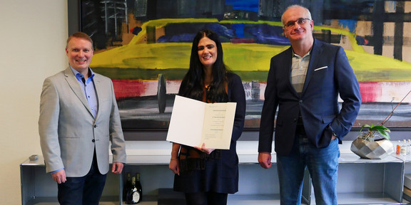Frau Sanchez Garcia präsentert ihre Ernennungsurkunde, rechts von ihr steht der Rektor Prof. Bayer, links von ihr steht Prof. Lütz, der Dekan der BCI